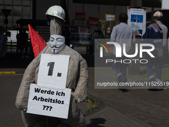 A dummy steelworker holds a sign reading ''Am I out of job?'' in front of the gate of the Thyssenkrupp industrial area in Duisburg, Germany,...