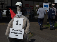 A dummy steelworker holds a sign reading ''Am I out of job?'' in front of the gate of the Thyssenkrupp industrial area in Duisburg, Germany,...