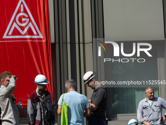 A thousand steel workers stand in front of the gate of the Thyssenkrupp industrial area in Duisburg, Germany, on August 29, 2024, as the IG...