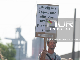 A thousand steel workers stand in front of the gate of the Thyssenkrupp industrial area in Duisburg, Germany, on August 29, 2024, as the IG...