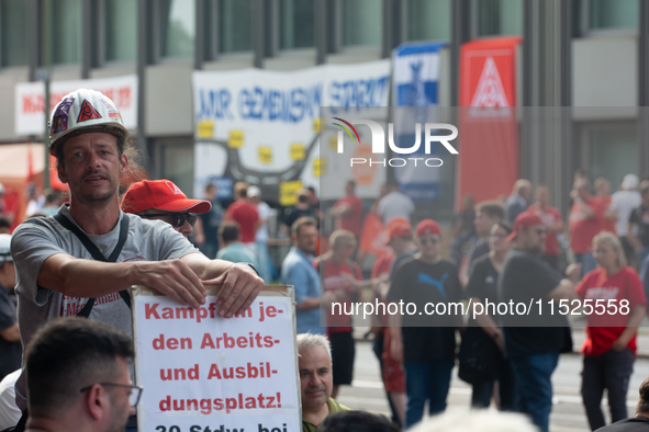 A thousand steel workers stand in front of the gate of the Thyssenkrupp industrial area in Duisburg, Germany, on August 29, 2024, as the IG...