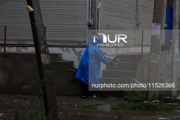 A man clears a bucket filled with rainwater in Sopore, Jammu and Kashmir, India, on August 30, 2024 