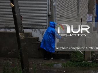 A man clears a bucket filled with rainwater in Sopore, Jammu and Kashmir, India, on August 30, 2024 (