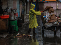 An employee of the municipality sweeps and puts garbage in a cart on a rainy day in Sopore, Jammu and Kashmir, India, on August 30, 2024. (