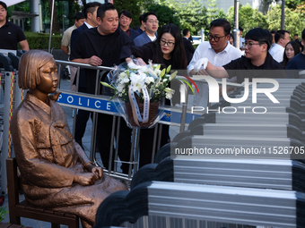 Members of the Democratic Party Youth Committee lay flowers in front of the Comfort Woman statue after holding the inauguration ceremony for...