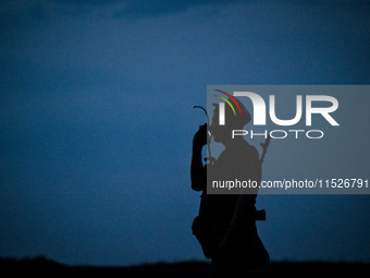 A serviceman of the 118th Separate Mechanized Brigade speaks into the radio during the night firing exercise in the Zaporizhzhia sector in t...