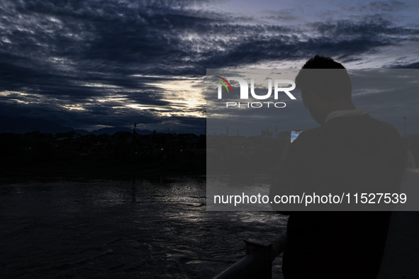 A young boy shoots video as clouds hover above during an evening in Sopore, Jammu and Kashmir, India, on August 30, 2024. 