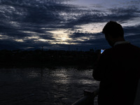 A young boy shoots video as clouds hover above during an evening in Sopore, Jammu and Kashmir, India, on August 30, 2024. (