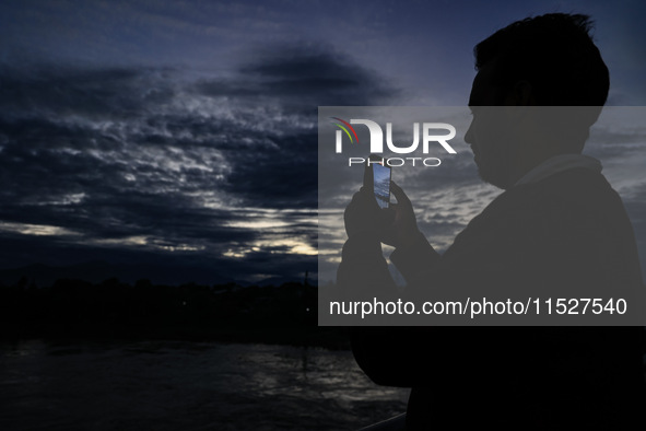 A young boy shoots video as clouds hover above during an evening in Sopore, Jammu and Kashmir, India, on August 30, 2024. 