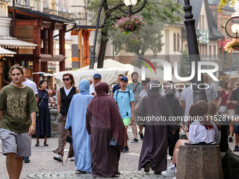 Families walk on a landmark Krupowki Street in the center of Zakopane, a popular Tatra mountain holiday resort on the last weekend of school...