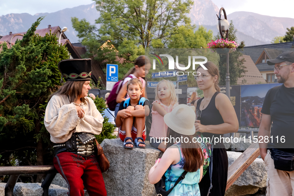 Family talk with a man dressed traditionally in Janosik style on a landmark Krupowki Street in the center of Zakopane, a popular Tatra mount...