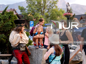 Family talk with a man dressed traditionally in Janosik style on a landmark Krupowki Street in the center of Zakopane, a popular Tatra mount...