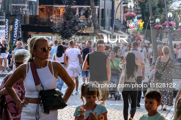 Families walk on a landmark Krupowki Street in the center of Zakopane, a popular Tatra mountain holiday resort on the last weekend of school...