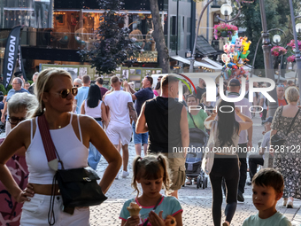 Families walk on a landmark Krupowki Street in the center of Zakopane, a popular Tatra mountain holiday resort on the last weekend of school...