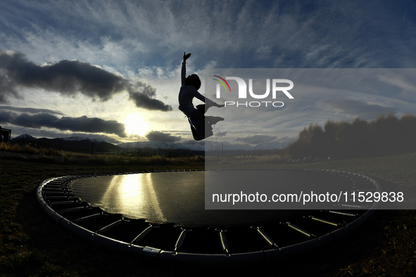 A little girl, Minudi Menulya, jumps on a trampoline in Twizel, New Zealand, on August 30, 2024. 