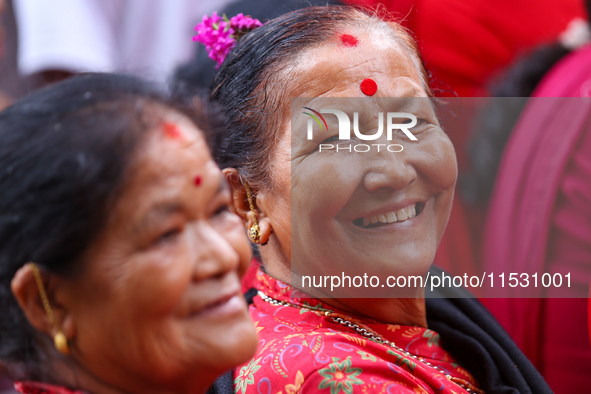 A Nepali devotee poses for a photo as she watches the parade of statues of Dipankar Buddha during the Panchadan festival in Bhaktapur, Nepal...