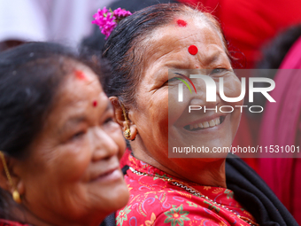 A Nepali devotee poses for a photo as she watches the parade of statues of Dipankar Buddha during the Panchadan festival in Bhaktapur, Nepal...