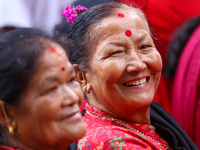 A Nepali devotee poses for a photo as she watches the parade of statues of Dipankar Buddha during the Panchadan festival in Bhaktapur, Nepal...