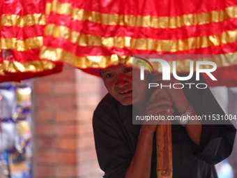 A Nepali devotee holds the umbrella for the statues of Dipankar Buddha during the Panchadan festival in Bhaktapur, Nepal, on August 31, 2024...