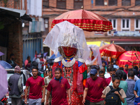 Nepali devotees carry the statues of Dipankar Buddha, covering them with plastic sheets as it rains heavily during the Panchadan festival in...