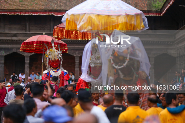 Nepali devotees carry the statues of Dipankar Buddha, covering them with plastic sheets as it rains heavily during the Panchadan festival in...