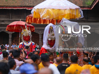 Nepali devotees carry the statues of Dipankar Buddha, covering them with plastic sheets as it rains heavily during the Panchadan festival in...