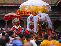 Nepali devotees carry the statues of Dipankar Buddha, covering them with plastic sheets as it rains heavily during the Panchadan festival in...