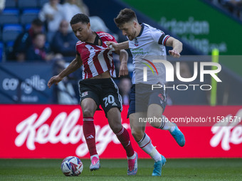 Jack Aitchison #10 of Exeter City F.C. is tackled by George Thomason #4 of Bolton Wanderers F.C. during the Sky Bet League 1 match between B...