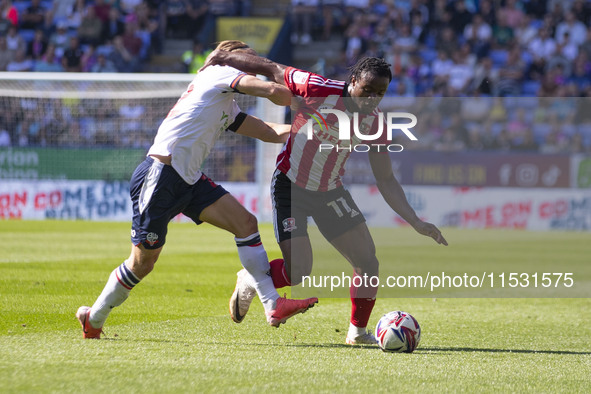 Millenic Alli #11 of Exeter City F.C. is tackled by Kyle Dempsey #22 of Bolton Wanderers F.C. during the Sky Bet League 1 match between Bolt...