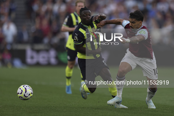 Jeremy Doku of Manchester City battles for possession with Lucas Paqueta of West Ham United during the Premier League match between West Ham...