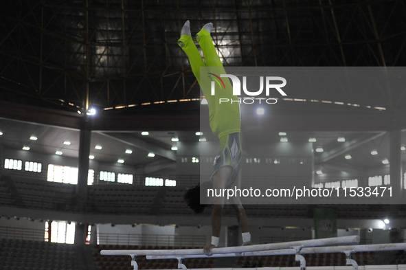 Gymnast from South Sulawesi, Rezha Saputra, competes in the Artistic Gymnastics competition on parallel bars in the men's group category at...