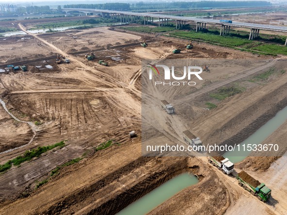 Excavators and trucks work in the river channel at the construction site of the second phase of the Huaihe River Waterway into the sea in Hu...