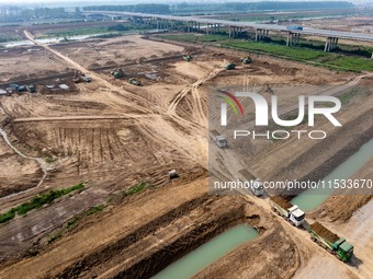 Excavators and trucks work in the river channel at the construction site of the second phase of the Huaihe River Waterway into the sea in Hu...