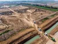 Excavators and trucks work in the river channel at the construction site of the second phase of the Huaihe River Waterway into the sea in Hu...