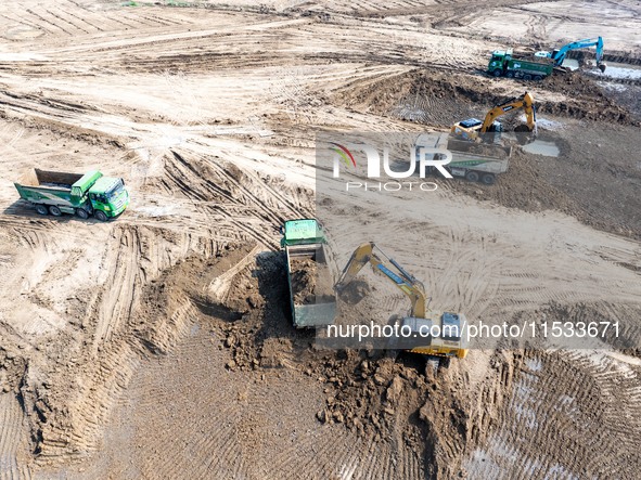 Excavators and trucks work in the river channel at the construction site of the second phase of the Huaihe River Waterway into the sea in Hu...