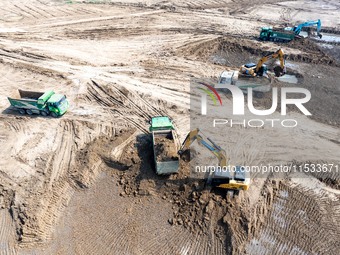 Excavators and trucks work in the river channel at the construction site of the second phase of the Huaihe River Waterway into the sea in Hu...