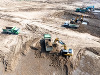 Excavators and trucks work in the river channel at the construction site of the second phase of the Huaihe River Waterway into the sea in Hu...