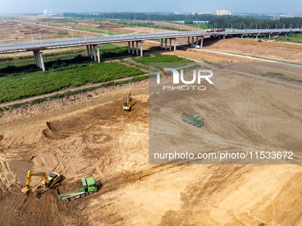 Excavators and trucks work in the river channel at the construction site of the second phase of the Huaihe River Waterway into the sea in Hu...