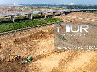 Excavators and trucks work in the river channel at the construction site of the second phase of the Huaihe River Waterway into the sea in Hu...