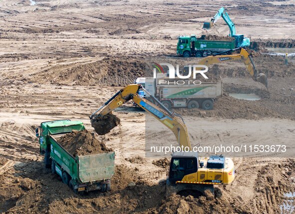 Excavators and trucks work in the river channel at the construction site of the second phase of the Huaihe River Waterway into the sea in Hu...