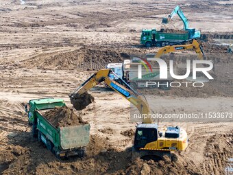 Excavators and trucks work in the river channel at the construction site of the second phase of the Huaihe River Waterway into the sea in Hu...