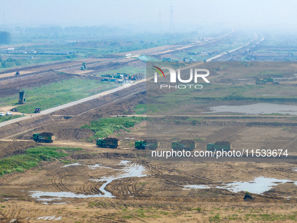 Excavators and trucks work in the river channel at the construction site of the second phase of the Huaihe River Waterway into the sea in Hu...