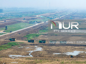 Excavators and trucks work in the river channel at the construction site of the second phase of the Huaihe River Waterway into the sea in Hu...