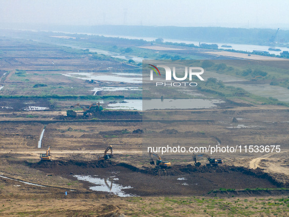 Excavators and trucks work in the river channel at the construction site of the second phase of the Huaihe River Waterway into the sea in Hu...