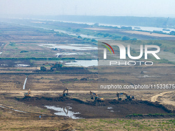 Excavators and trucks work in the river channel at the construction site of the second phase of the Huaihe River Waterway into the sea in Hu...