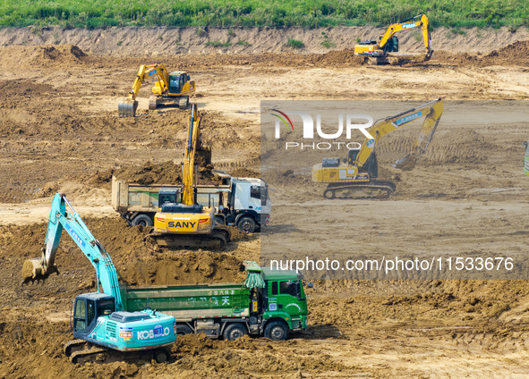 Excavators and trucks work in the river channel at the construction site of the second phase of the Huaihe River Waterway into the sea in Hu...