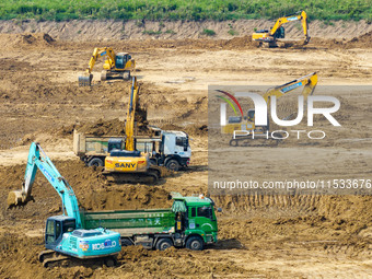 Excavators and trucks work in the river channel at the construction site of the second phase of the Huaihe River Waterway into the sea in Hu...