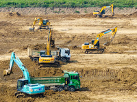 Excavators and trucks work in the river channel at the construction site of the second phase of the Huaihe River Waterway into the sea in Hu...