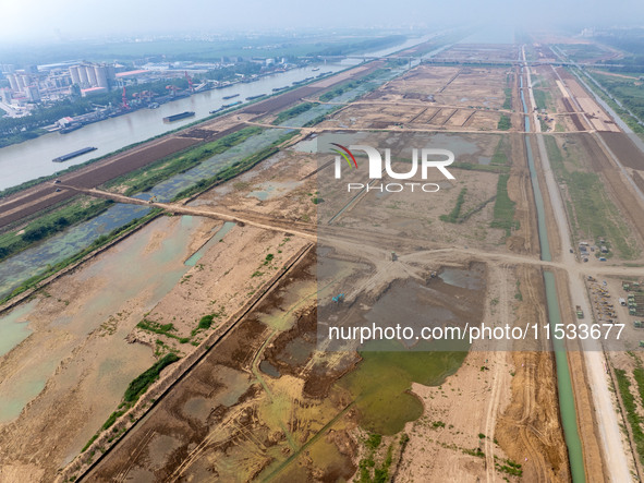 Excavators and trucks work in the river channel at the construction site of the second phase of the Huaihe River Waterway into the sea in Hu...