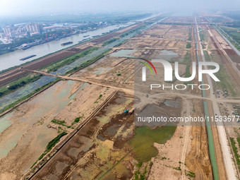 Excavators and trucks work in the river channel at the construction site of the second phase of the Huaihe River Waterway into the sea in Hu...